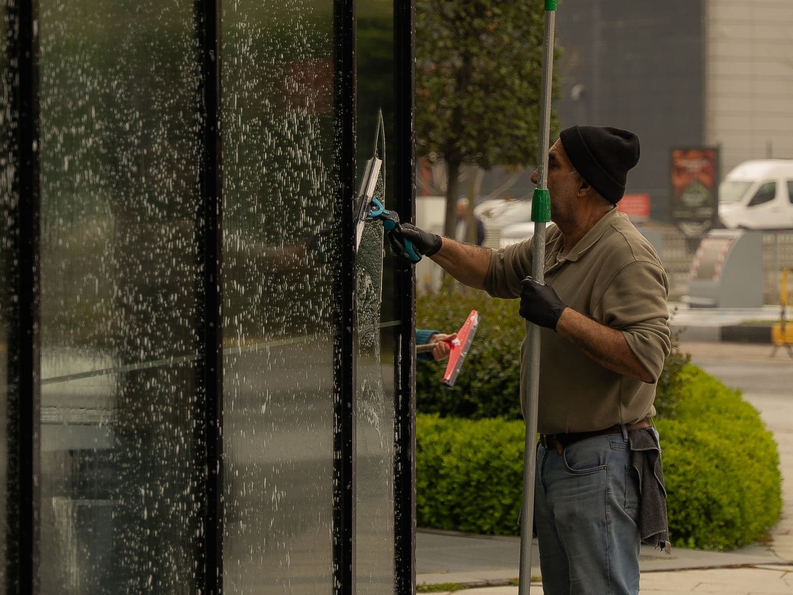 Professional cleaner using a squeegee on large commercial interior windows